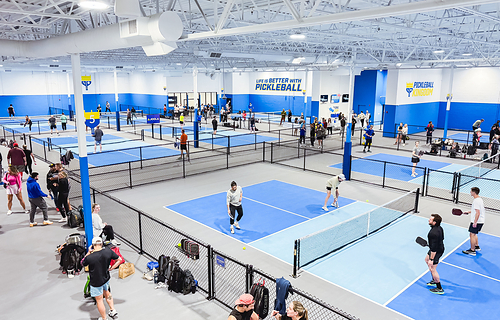 Inside a Pickleball Kingdom location featuring multiple indoor courts. Inside a Pickleball Kingdom location featuring multiple indoor courts.