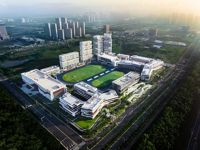 Overhead view of GGU China Center in Wuhan. Large white buildings engulf two green sports fields, in front of a stunning backdrop of the city skyline.