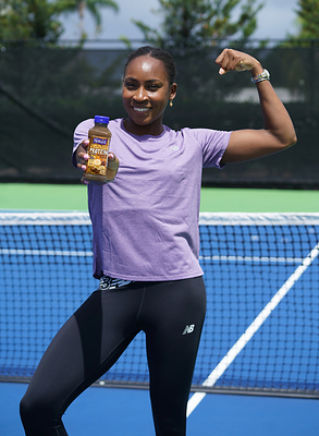 Coco Gauff, professional tennis player and Naked Chief Smoothie Officer, enjoys the NEW Naked Chocolate Banana Protein Smoothie courtside.