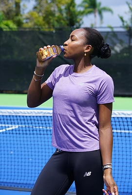 Coco Gauff, professional tennis player and Naked Chief Smoothie Officer, enjoys the NEW Naked Chocolate Banana Protein Smoothie courtside.