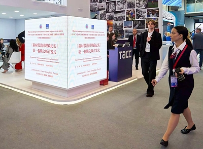People walk past screens displaying information of the launch ceremony of the Russian edition of the first volume of "China's Governance Under Xi Jinping's Leadership" at the 29th St. Petersburg International Economic Forum in St. Petersburg, Russia, June 3, 2026. (Photo by Guo Feizhou/Xinhua)