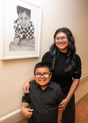 CSUMB student artist Zugey Velasco and brother Zayn with her work titled "Growing Beside You."