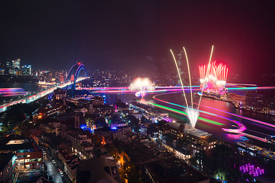 Imagen panorámica nocturna de Sídney en la que se aprecia el festival Vivid Sydney 2026, con fuegos artificiales que iluminaron el cielo sobre la Ópera de Sídney y el Puente del Puerto
