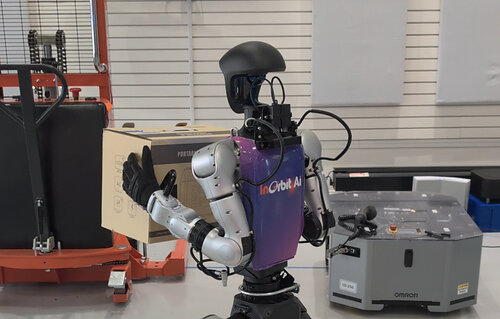 Humanoid robot carrying a box in front of a mobile robot and pallet stacker managed by InOrbit Space Intelligence.
