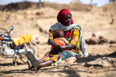 In Sudan, a mother holds her baby, who is suffering from malnutrition. On World Refugee Day, new research highlights how funding cuts are deepening hunger for displaced families.