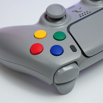 Close-up of Killscreen SFC-1, highlighting its SNES-inspired multicolor face buttons, soft gray finish, and PC + PS5 controller design.