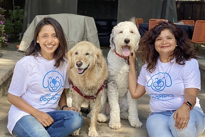 DogHood Co-Founders Purvi Janardhan (right) and Ruchi Joshi (left) sit with Oreo the Sheepadoodle and Nessie the Golden Retriever to celebrate the platform's major product expansion.