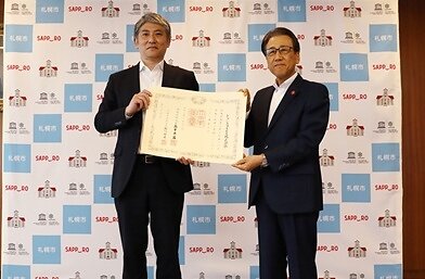 Medal of Dark Blue Ribbon presentation ceremony Right: Katsuhiro Akimoto, Mayor of Sapporo City Left: Masanori Sato, Corporate Senior Officer & Deputy Sector Manager, DCC Sector, CX Business Headquarters, transcosmos