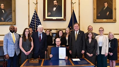 People working to promote improved energy access attend the ceremonial signing of Senate Enrolled Act 240 at the Indiana State Capitol on April 14. Governor Mike Braun (R), center, signed the bill authored by State Senator Eric Koch (R) and co-sponsored by State Representative Edmond Soliday (R), who stand to the right and left of Gov. Braun, respectively. Jenny Netherton, who works on The Pew Charitable Trust' energy modernization project, is third from the left.