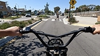 A first-person view from behind the handlebars of a teen entering an intersection on an ebike