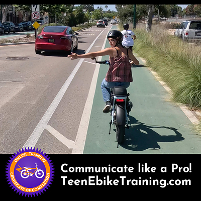 A teen on an ebike in a bike lane making a proper hand signal to turn left out of the lane.