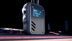 TACCOM v2 radio standing on a desk mat beside a backlit gaming keyboard and mouse