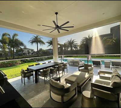 Fenetex MaxForce Retractable Hurricane Screens surround a residential patio that overlooks palm trees and a swimming pool