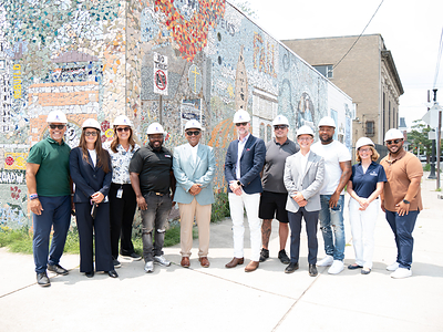 Representatives from New Jersey American Water, IDEA Center for the Arts, Mighty Writers, Heart of Camden, Ed’s Contracting Services, American Water Charitable Foundation, and American Water pose for a group photo in front of a community mural at 526 Ferry Avenue, Camden, NJ. 