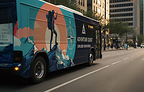 A city bus is wrapped with large-format graphics featuring an outdoor adventure campaign, demonstrating how printed media can transform vehicle surfaces into mobile brand communication platforms.