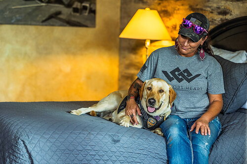 Michelle "Cash" Axmaker sits with a K9 at the Warriors Heart campus in Bandera, Texas.