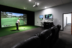 Golfer playing inside a private Cave at GolfCave on a Trackman simulator, viewing real-time shot data and analytics on screen.
