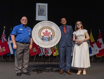 (From left to right) Royal Canadian Legion Dominion President Berkley Lawrence, Royal Canadian Mint Interim President and CEO Simon Kamel, and artist Vlada Paschenko unveil a two-dollar circulation coin celebrating the 100th anniversary of The Royal Canadian at the Legion’s Dominion Convention in Winnipeg, Manitoba on August 24, 2026.