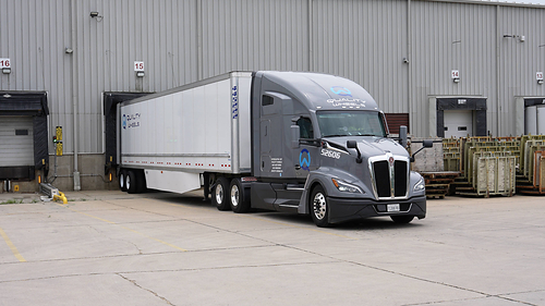 A modern Quality Wheels Inc. dry van truck positioned at a loading dock, ready for FTL freight dispatch.