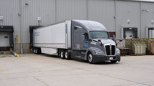A modern Quality Wheels Inc. dry van truck positioned at a loading dock, ready for FTL freight dispatch.