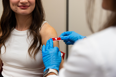Pharmacist placing bandage on patient who received a vaccination. 