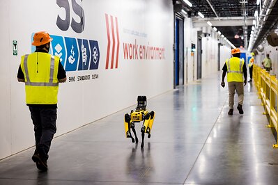 Purina employees and robot dog, Spot, walk the hall of Purina’s new pet food factory in Ohio during its grand opening on August 31, 2026. Spot, created by Boston Dynamics, is trained to conduct thermal and acoustic inspections of machinery as part of the factory’s digital manufacturing program. 