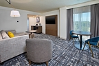 A renovated king corner suite at Crowne Plaza Bowling Green features a spacious living area, dining and workspace options, and modern in-room amenities.