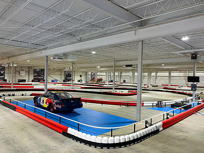 The indoor go-karting track at K1 Speed Cleveland features a stock car on display inside the safety barriers.