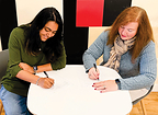 Robbie Adair, CEO of OS Training LLC, and Vinitra Swamy, CEO of Scholé AI, sign partnership agreement.