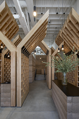 Olive-tree-inspired wooden structures create a series of pathways through OLIVE TREE PEOPLE’s Venice flagship, alongside rammed-earth walls and counters used throughout the space.