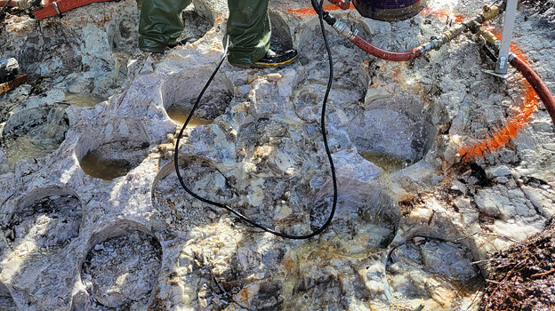 Figure 2: (TOP) Cored drill hole (~30 cm diameter) in pollucite pegmatite outcrop; (BOTTOM) Grid of cored drill holes (~30 cm diameter) in pollucite pegmatite outcrop (see Table 1). Segments between holes are jackhammered out and added to sample composite.