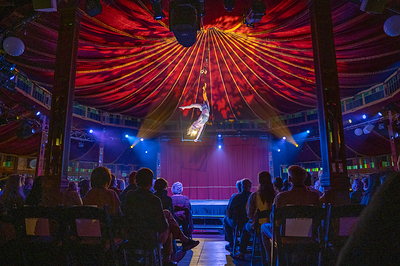 An aerialist soars high above the crowd in the Spiegeltent at the ESL Rochester Fringe Festival. Photo Credit: Keith Bullis. 