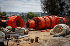 Large reels of orange electrical conduit and construction materials at the project site.