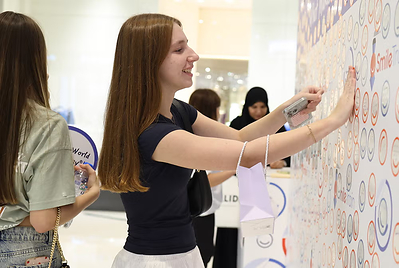 Participants add their smiles to a colorful community “Smile Wall,” creating a cheerful shared display.