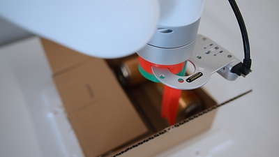 BoxBot, a Viam research robot that cuts the tape on sealed cardboard boxes and opens the flaps. Shown from overhead, the side, and up close at Viam’s robotics lab in New York City.