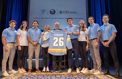 New York Islanders Co-Owner Jon Ledecky is presented with an honorary LIU hockey jersey, featuring the captain’s “C,” alongside members of the LIU men’s and women’s hockey teams during the University’s CEO Speaker Series.