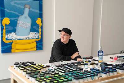 KAWS in his Brooklyn studio with the specially commissioned painting that inspired the ABSOLUT KAWS Artist Edition Bottle. KAWS in his Brooklyn studio with the specially commissioned painting that inspired the ABSOLUT KAWS Artist Edition Bottle.