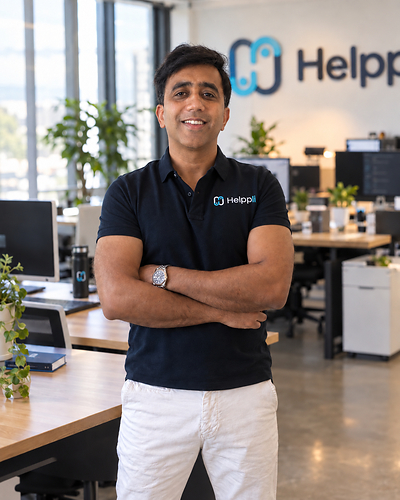Niroj Sri, CEO of Helppli poses in the Helppli office with his arms crossed and a welcoming smile.