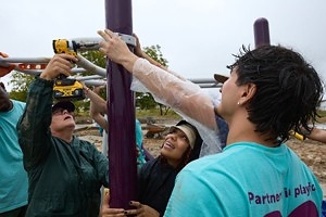 Many hands, one post. Volunteers bolt the climbing frame together in the rain. Many hands, one post. Volunteers bolt the climbing frame together in the rain.