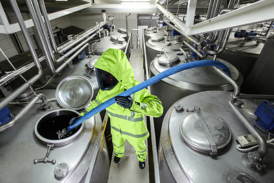 Worker performing liquid transfer in PIP® Multi-Hazard Suit with GORE-TEX® PYRAD® Fabric.