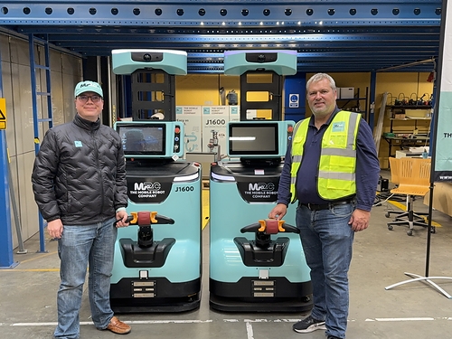 Emil Hauch Jensen and Odin Kudahl Skovsted, founders of The Mobile Robot Company with two of their J1600 self-driving pallet jacks.
