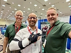 Mark Szymanski (center), CEO at Evocati PR, poses wearing the Carbonhand® alongside representatives from Bioservo at Paralyzed Veterans of America's Healthcare Summit + Expo 2026. (Source: Evocati PR)