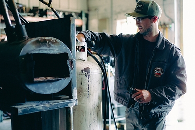 Liam Hoffman, founder of Tennessee-based Hoffman Blacksmithing and Hoffman Handles, crafts a custom Pulaski for the Seager Co. x Coors Banquet Protect Our Protectors campaign, honoring the skill and dedication of America's wildland firefighters.