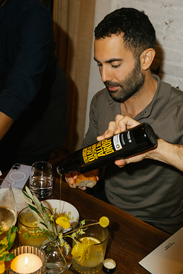 Andy Baraghani drizzles Spanish extra virgin olive oil over bread during an Olive Oils From Spain dinner at The Musket Room. The evening celebrated the Spanish tradition of sobremesa and the versatility of Spanish olive oils in everyday cooking. Photo courtesy of Olive Oils From Spain.