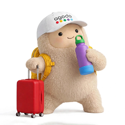 Jolly, from Meta's Muse, is shown wearing a cap with the Agoda logo and holding a water bottle next to a suitcase.