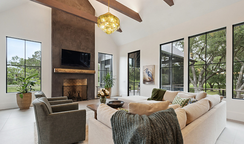 Twenty-one-foot ceilings with exposed wood beams create volume in the living room. A rustic reclaimed-wood mantel and classic herringbone brick fireplace box add texture and warmth. Twenty-one-foot ceilings with exposed wood beams create volume in the living room. A rustic reclaimed-wood mantel and classic herringbone brick fireplace box add texture and warmth.