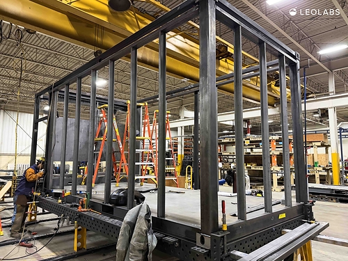 An engineer is shown building the "chassis" or framework of a LeoLabs Scout-S that will be delivered in early 2027.